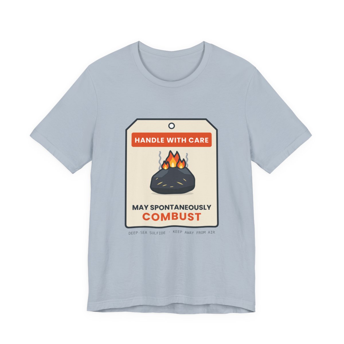 Light blue t-shirt printed with a cream specimen tag reading HANDLE WITH CARE above a smoldering rock and MAY SPONTANEOUSLY COMBUST