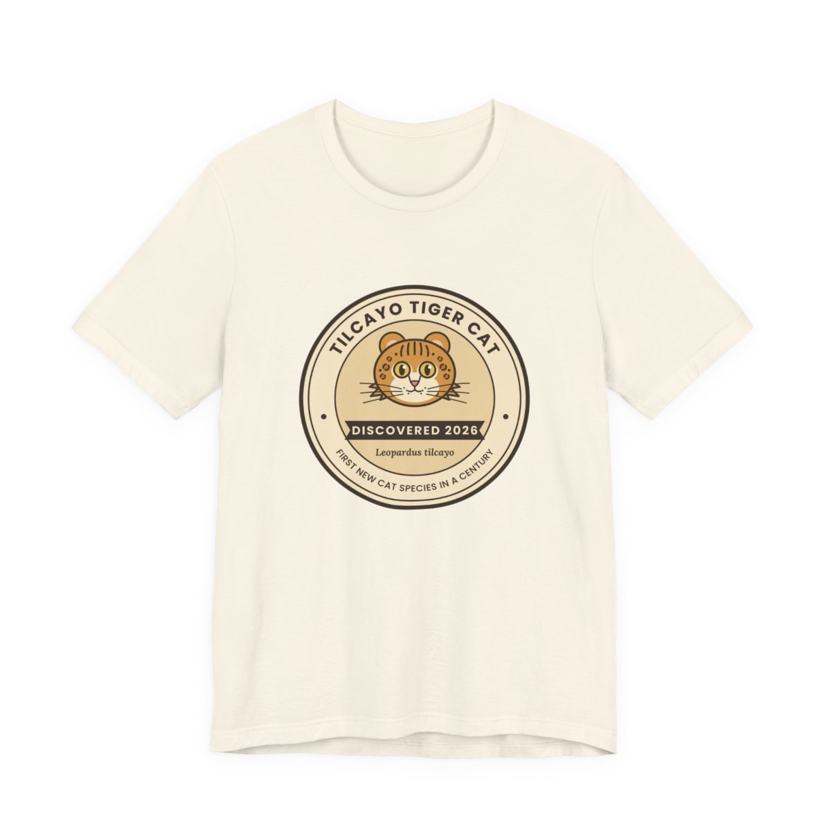 Natural-color t-shirt with the round Tilcayo Tiger Cat Discovered 2026 badge on the chest